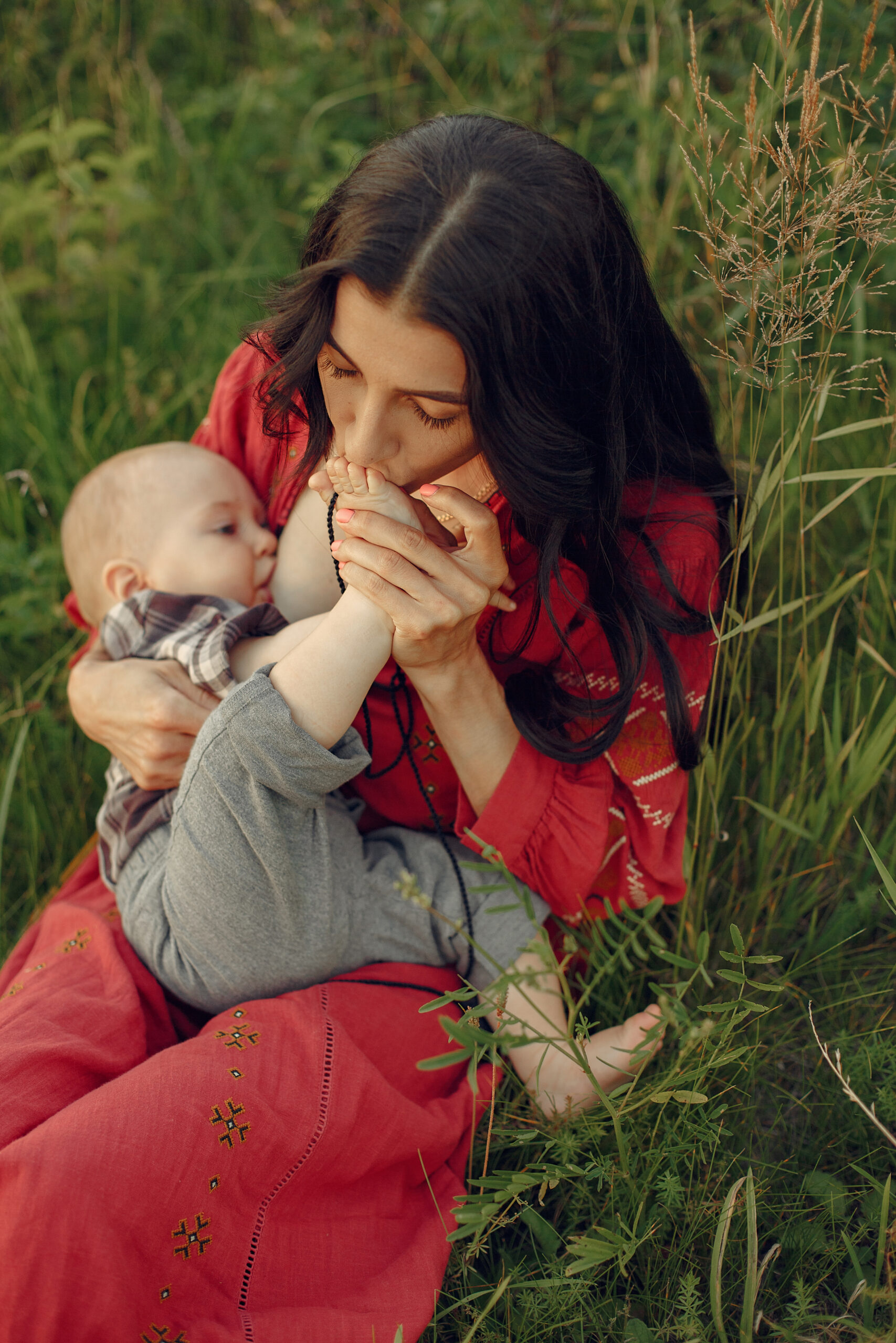 woman sitting on a blanket and breastfeeding her little son