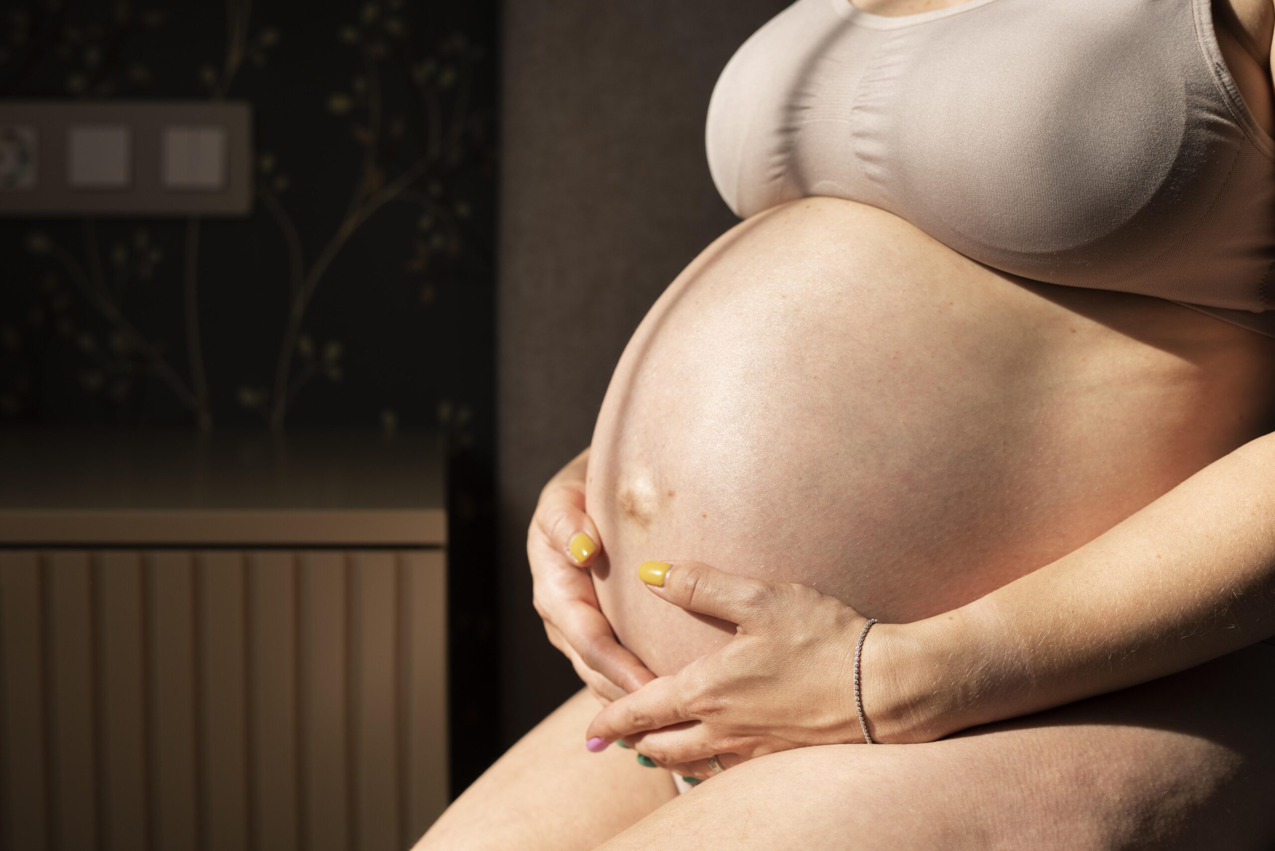 close up pregnant woman holding tummy